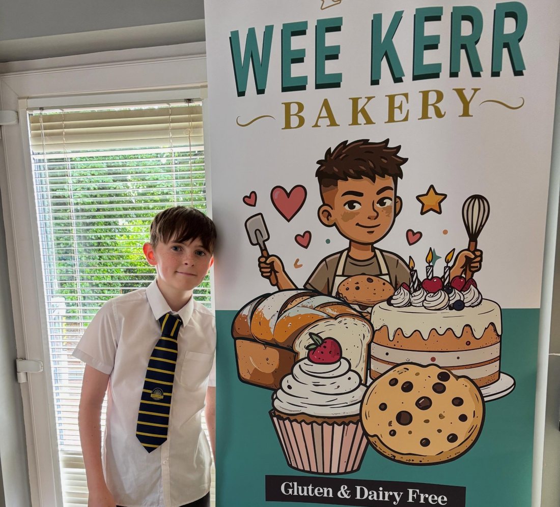 Oscar standing beside his Wee Kerr Bakery pop-up banner